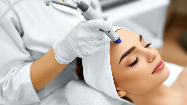 Esthetician performing microdermabrasion forehead exfoliation treatment