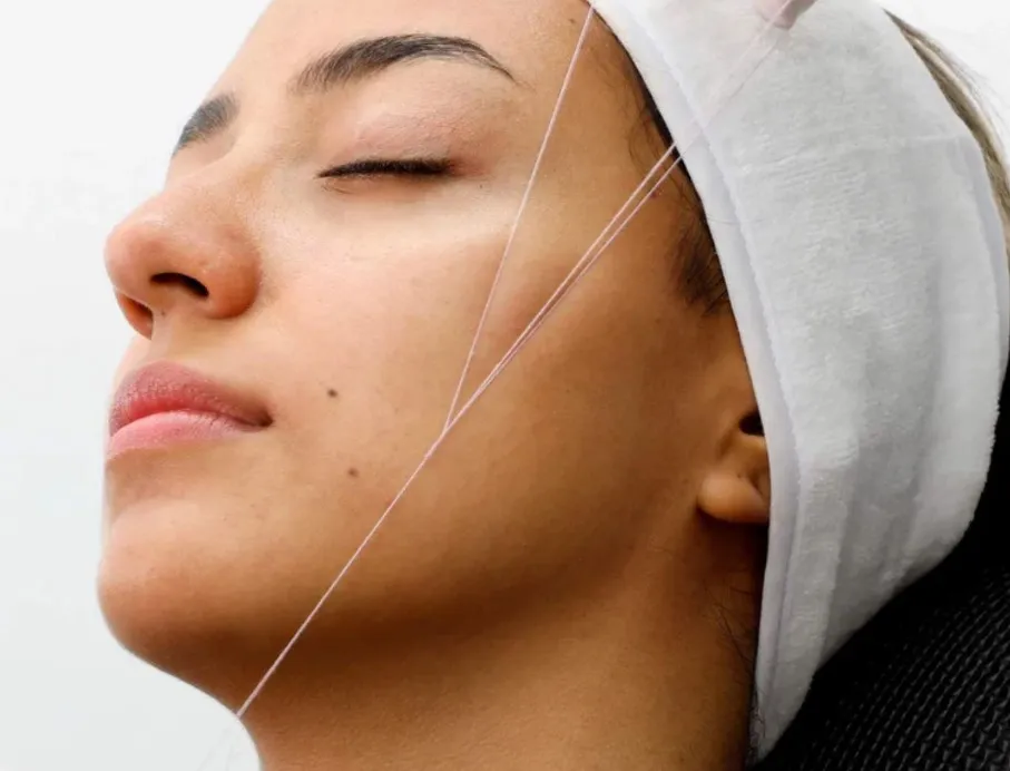 Certified esthetician performing full face facial threading hair removal