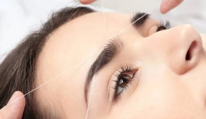 Professional eyebrow threading salon procedure in progress